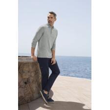 Gris chiné Mann mit grauem Pima-Interlock-Polo, steht an einer Steinmauer mit Meerblick.