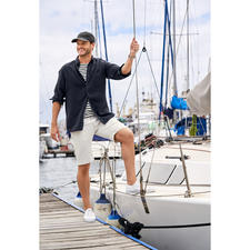 Manches courtes, Écru/Marine Mann in gestreiftem Herren-Bretagne-Shirt an Bord eines Bootes.