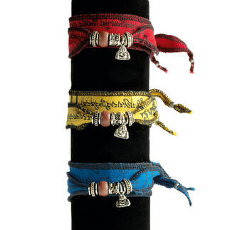 Drei tibetische Wunsch-Armbänder in rot, gelb und blau mit Silberanhängern.