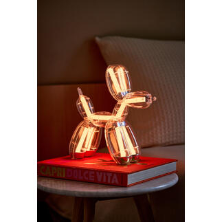 Ballonhund-Lampe auf einem Buch, warm-weiß leuchtend.