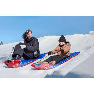 Mann zieht XL-Schneegleiter mit einem Kind auf einer schneebedeckten Landschaft.