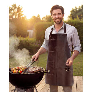 Mann grillt mit Büffelleder-Grillschürze am Grill im Garten.