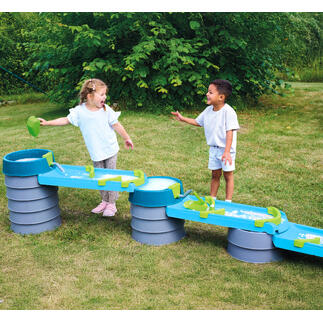 Zwei Kinder lachen und spielen an der Wasser- und Matschbahn.