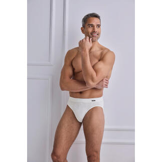 Mann in weißem Cult-Slip zeigt muskulöse Pose.
