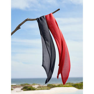 Schwarz-roter gestrickter Seidenschal hängt an einem Ast am Strand.