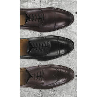 Drei Cordwainer Business-Schuhe in verschiedenen Brauntönen nebeneinander auf einer Steinoberfläche.
