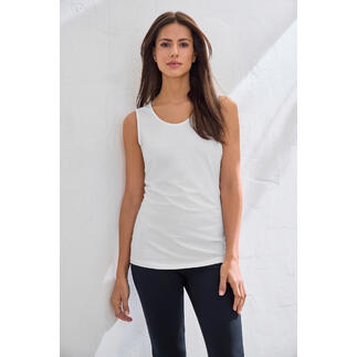 Weißes Basic-Top aus Swiss Cotton auf einer hellen Wand.