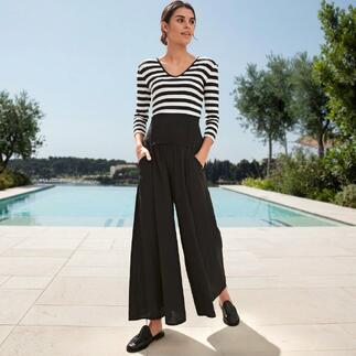 Frau in gestreiftem Zauber-Shirt mit schwarzer Hose, steht vor Schwimmbad.