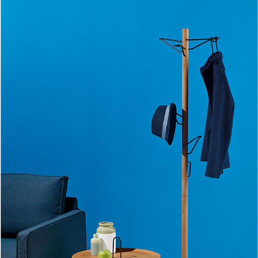 Standgarderobe aus Holz mit Jacke und Hut in einem modernen Raum.