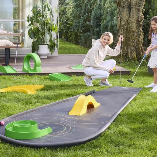 Frau mit Kind spielt Minigolf auf einem mitgenommenen Minigolfplatz.