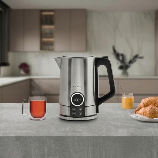 Moderner Edelstahl Wasserkocher auf einer Arbeitsplatte mit einer Tasse Tee und einem Croissant.