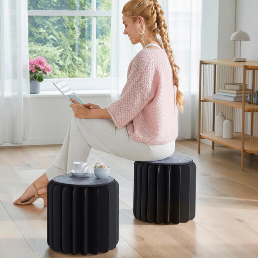 Frau auf einem Bookniture Hocker mit Tablet in einem eleganten Raum.