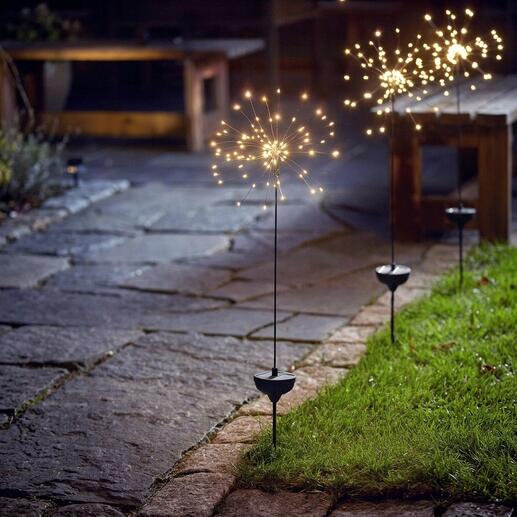 Solar-Wunderkerze leuchtet im Garten auf einem Steinweg.