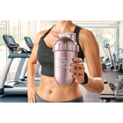 Frau hält einen rosa Shaker in einem Fitnessstudio.