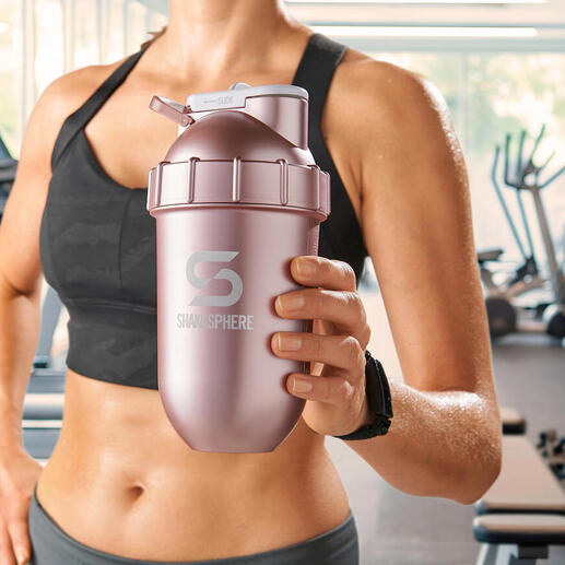 Frau hält einen rosa Shaker in einem Fitnessstudio.