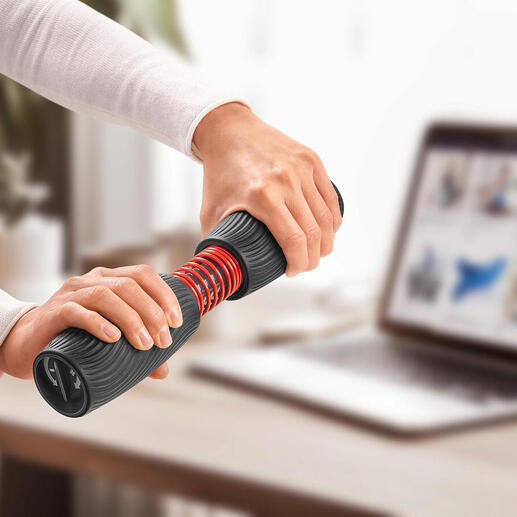 Person trainiert mit Handgelenk- und Unterarmtrainer an einem Tisch mit Laptop.