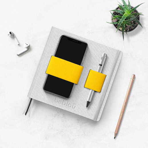 Flex-Book mit Smartphone, Stift und Pflanze auf einem Tisch.