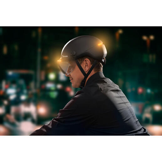 Mann trägt einen Fahrradhelm mit Lichtsignal in der Stadt bei Nacht
