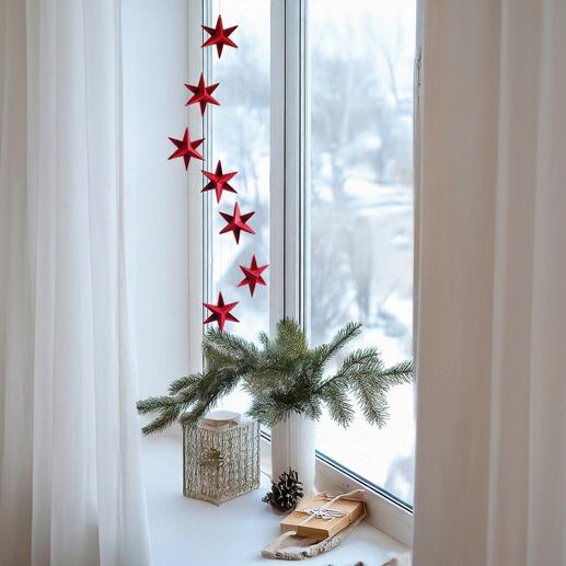 Rotes Mobiles Sternendekor über einer Fensterbank mit Schnee draußen.