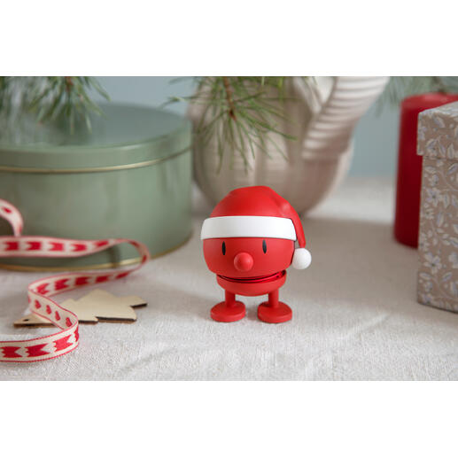 Hoptimist Schneemann mit rotem Weihnachtsmütze auf festlichem Tisch.