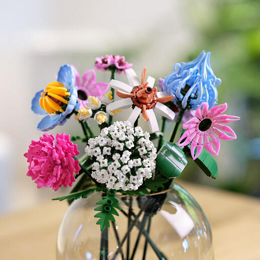 Blumenstrauß aus Klemmbausteinen in Rosé- und Lilatönen in einer Vase.