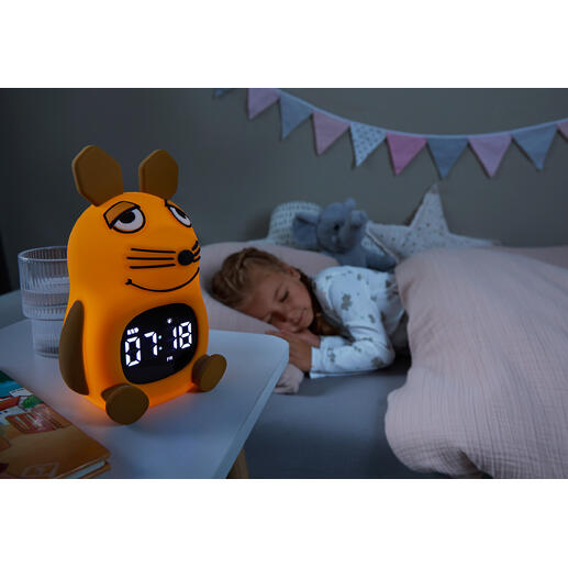 DieMaus Lichtwecker für Kinder auf einem Nachttisch neben schlafendem Mädchen.