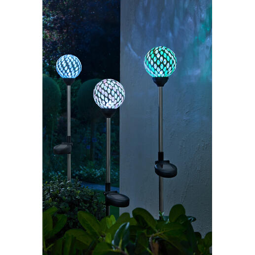 Drei Solargartenstecker mit bunten Mosaiklampen im Garten.