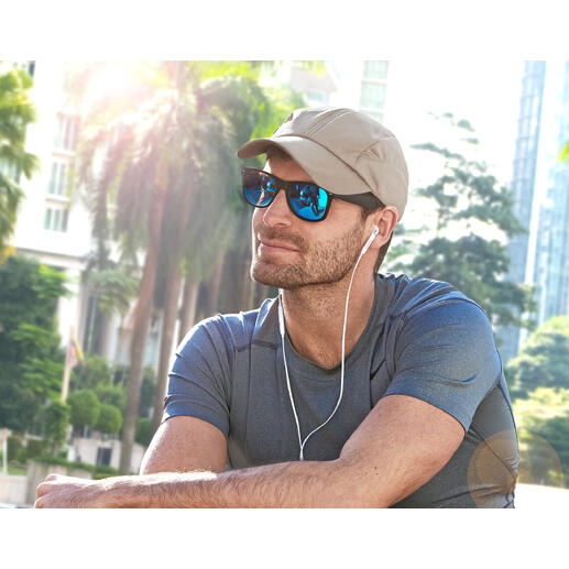 Mann mit beige Kühlkappe und Sonnenbrille sitzt im Freien