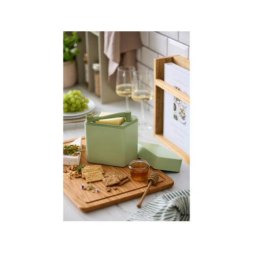 Käse Frischebox mit Schneider auf einem Holzbrett neben Crackern und Honig.