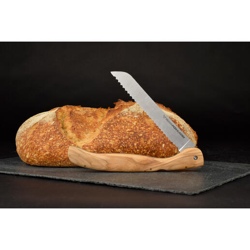Klappbares Brotmesser mit Olivenholzgriff neben einem Laib Brot auf einer schwarzen Unterlage.
