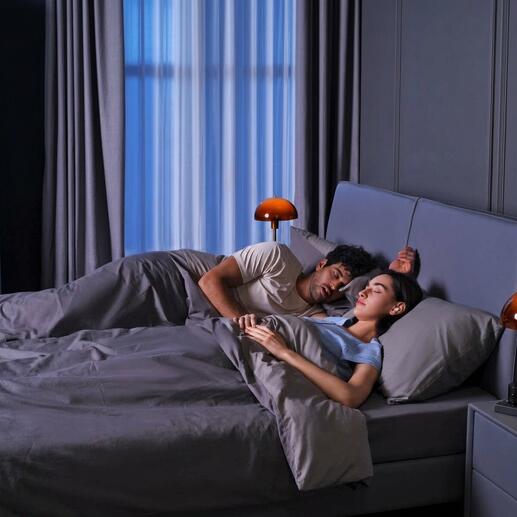 Paar schläft im Bett, Ohrhörer-/Schlafstöpsel auf dem Kopfkissen.