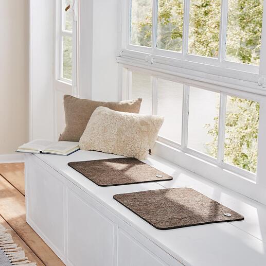 Zwei hellbraune Alpaka-Sitzunterlagen auf einer Fensterbank.