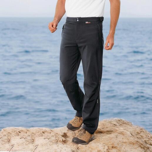 Mann in schwarzen Softshell-Hosen steht am Meer.