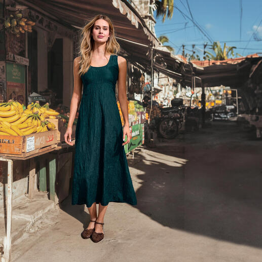 Frau in sticktem grünem Seidencrash-Kleid vor einem Markt.