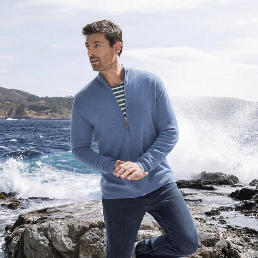 Mann in blauer Kaschmir-Sweatjacke, am Meer stehend.