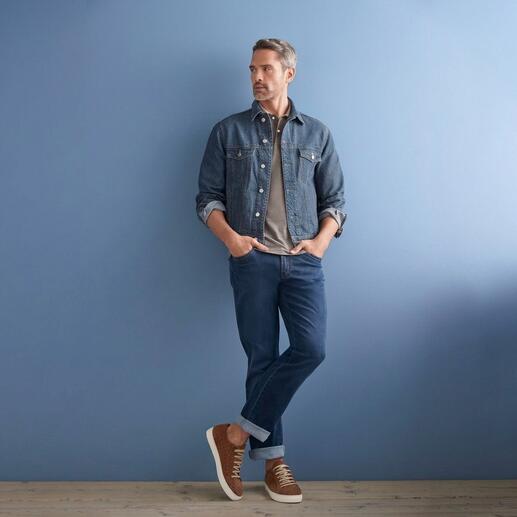 Mann in OCONI Hanf-Jeansjacke vor blauem Hintergrund, mit Jeans und Sneakers.