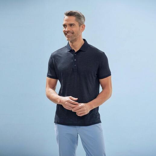 Schwarz gekleideter Mann mit dunkelgrau-blauem Polo auf blauem Hintergrund.