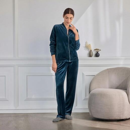Frau trägt grünen Hanro Loungewear-Samt-Anzug, entspannt in moderner Umgebung.