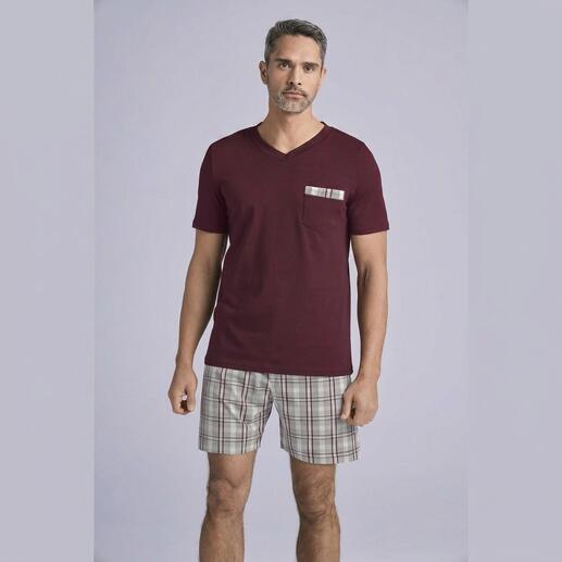 Mann in burgunderfarbenem T-Shirt mit kariertem Hut, trägt karierte Shorts.