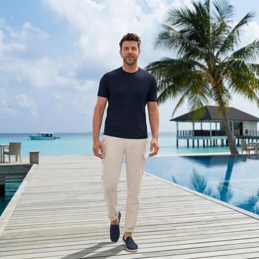 Mann in dunkelblauem T-Shirt und beigen Hosen läuft auf einer Holzterrasse.