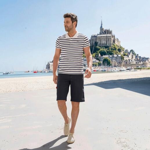 Mann in gestreiftem Saint James Bretagne-Poloshirt beim Spazieren am Strand.