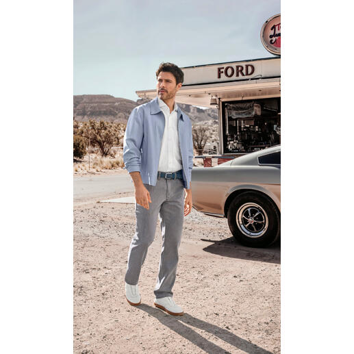 Leinen-Lyocell-Sommerblouson Mann in hellblauem Sommerblouson, steht vor einem Diner.