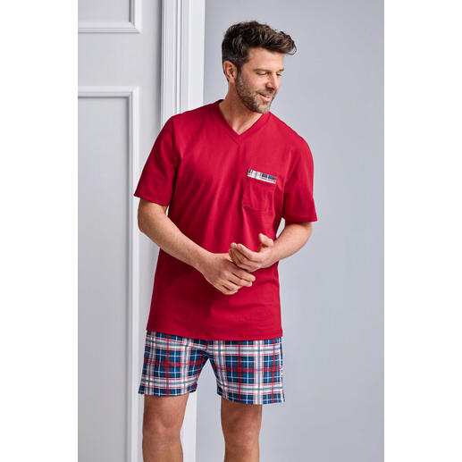 Mann trägt einem roten Pyjama mit karierten Shorts in Blau und Weiß.