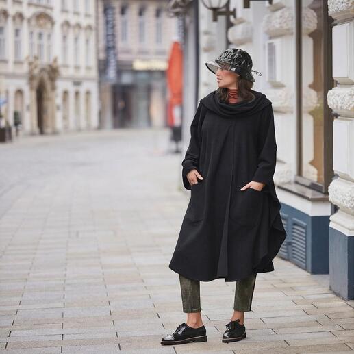 Frauenmodel trägt schwarzen Cape-Mantel, steht in der Stadt.