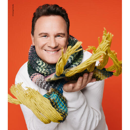 Charity Paket mit einem bunten Schal, präsentiert von einem lächelnden Mann.