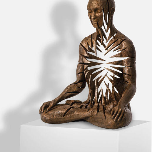 Skulptur eines sitzenden Mannes mit aufgerissenem Herzen und strahlenden Linien.