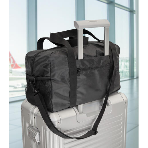Exklusive faltbare Reisetasche auf einem Koffer im Flughafen.