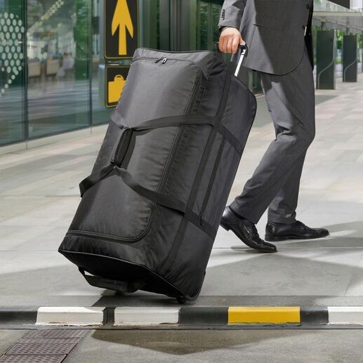 Schwarze Ultraleicht-XXL-Reisetasche wird von einem Mann im Anzug geschoben.