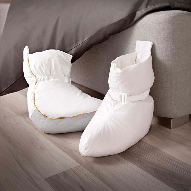 Bettschuhe aus weichem Material auf einem Holzfußboden.