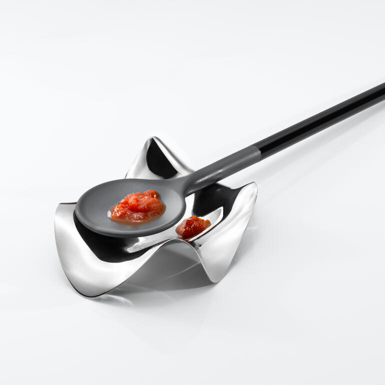 Design-Kochlöffelhalter Moderner Kochlöffelhalter mit schwarzem Löffel und Sauce.